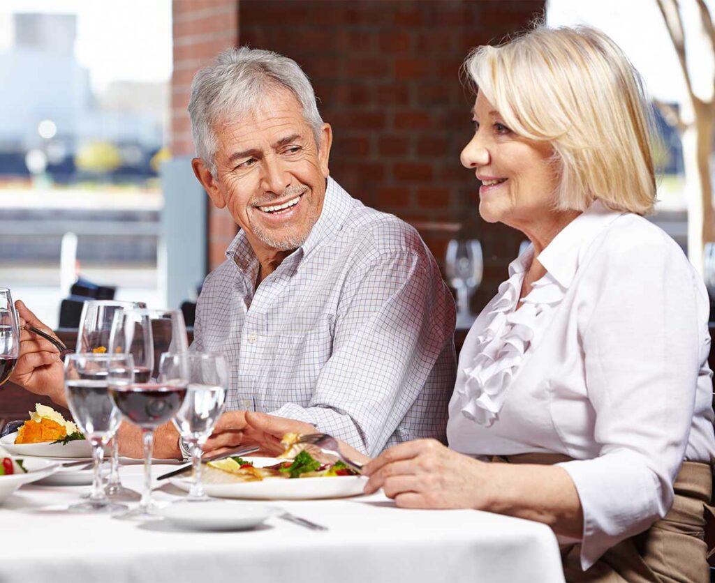 senior couple smiling and enjoying a complimentary gourmet meal at a seminar